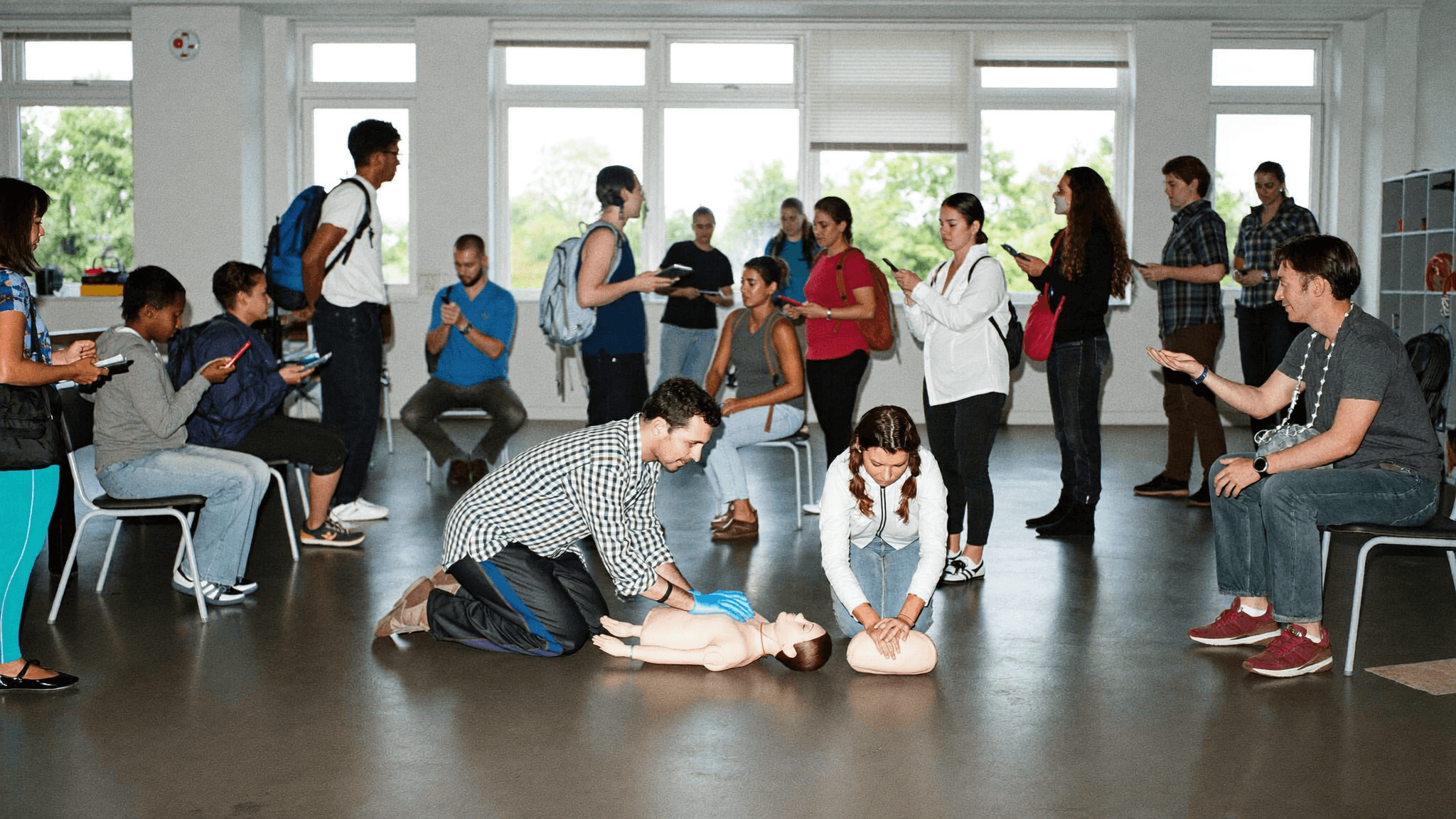 Adult learners practising first aid in a daylight training classroom